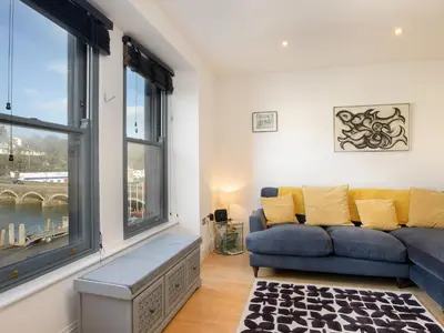a living room with a blue couch and large windows at Water View in Looe