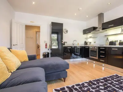 a living room with a couch and a kitchen at Water View in Looe