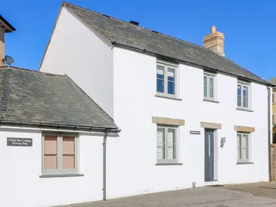 a white house with a black roof at Fistral Bay Cottage in Newquay