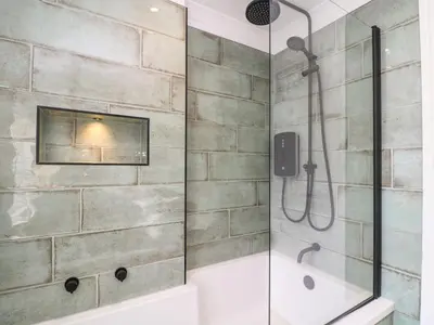 a bathroom with a shower with a glass door at Fistral Bay Cottage in Newquay
