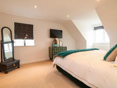 a bedroom with a bed and a mirror and a tv at Trevose House in Newquay