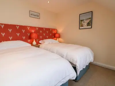 a bedroom with two beds and a red headboard at Trevose House in Newquay