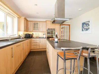 a kitchen with wooden cabinets and a island with bar stools at Trevose House in Newquay