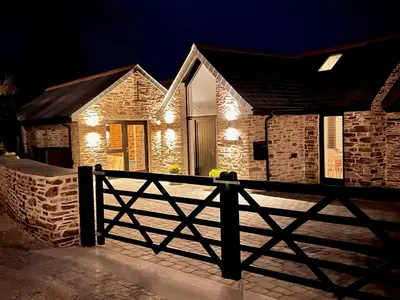 a house with a fence in front of it at night at Gwel an Heyl, Padstow in Little Petherick