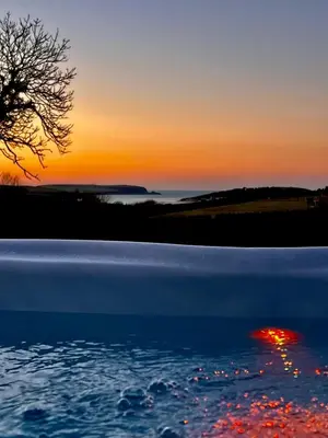 a sunset over a body of water with a tree at Gwel an Heyl, Padstow in Little Petherick