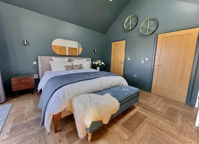 a bedroom with a large bed with blue walls at Gwel an Heyl, Padstow in Little Petherick
