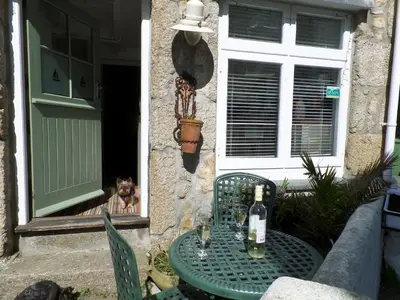 a dog looking out of a window with a table with wine bottles at Labour in Vain in St Ives