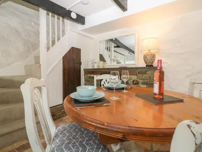 a dining room with a wooden table and wine glasses at Pixie Cottage in Looe