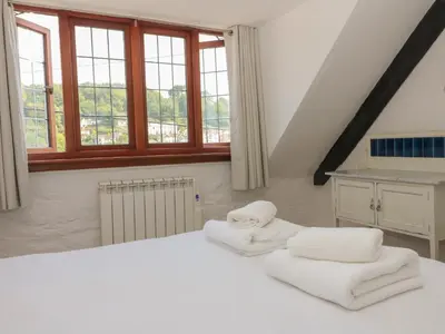 a bedroom with white towels on a bed with windows at Pixie Cottage in Looe