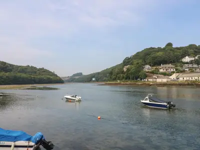 three boats floating on a river with mountains in the background at Pixie Cottage in Looe