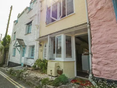 a pink and yellow house on the side of a street at Pixie Cottage in Looe