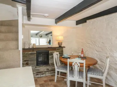 a dining room with a table and chairs and a fireplace at Pixie Cottage in Looe