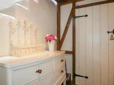 a white dresser with a vase of flowers on top of it at Coinage Hall in Lostwithiel