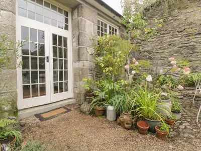 a garden with potted plants in front of a house at Coinage Hall in Lostwithiel