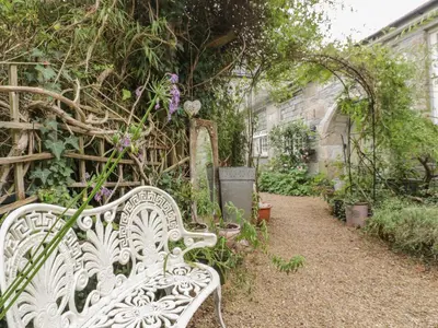 a white bench sitting in a garden with plants at Coinage Hall in Lostwithiel