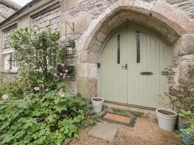 a white garage door in a stone building with plants at Coinage Hall in Lostwithiel