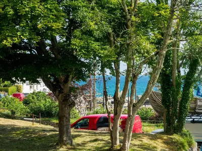 a red car parked in a park with trees at The Old Smoke House in St Austell