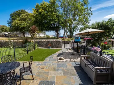 a patio with a table and chairs and an umbrella at The Old Smoke House in St Austell