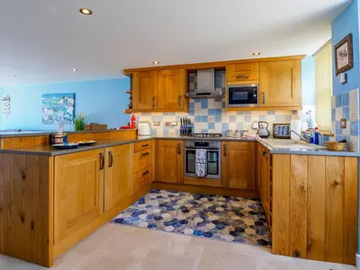 a kitchen with wooden cabinets and a stove top oven at The Old Smoke House in St Austell