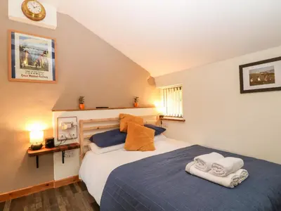 a bedroom with a large bed with two towels at Elvan Cottage in Liskeard
