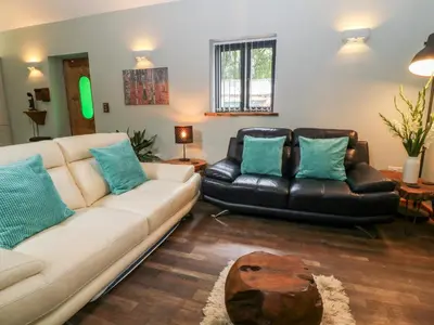 a living room with a white couch and a black leather chair at Elvan Cottage in Liskeard