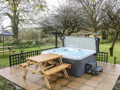 a hot tub with a picnic table and a bench at Elvan Cottage in Liskeard