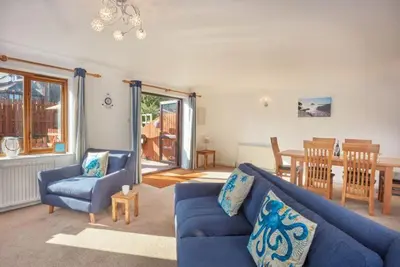 a living room with a blue couch and a table at Trevells in Wadebridge