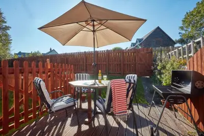 a table and chairs with an umbrella and a laptop at Trevells in Wadebridge