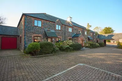 a large brick house with a red garage at Trevells in Wadebridge