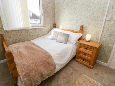 a bedroom with a bed with white sheets and a night stand at Valhalla in St Ives