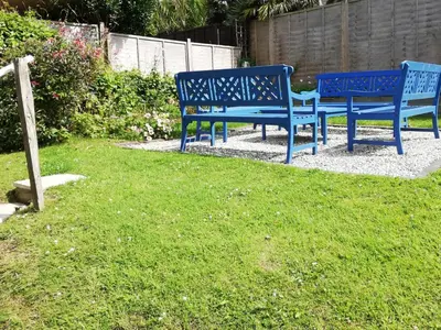 two blue benches sitting on the grass in a yard at Valhalla in St Ives