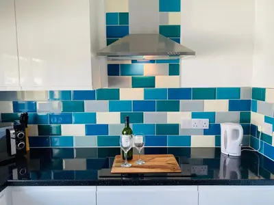 a kitchen counter with a bottle of wine and two glasses at Driftwood Seagrass in Par