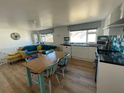 a kitchen and living room with a wooden table and a dining room at Driftwood Seagrass in Par