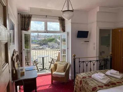 a bedroom with a bed and a table and a window at Harbour Hotel in Newquay