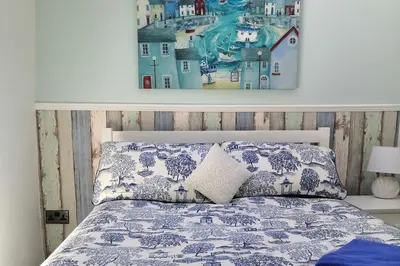 a bedroom with a bed with a painting on the wall at 1 Bed Cottage-Sleeps 3-Pool-Pets-near St Ives in Camborne