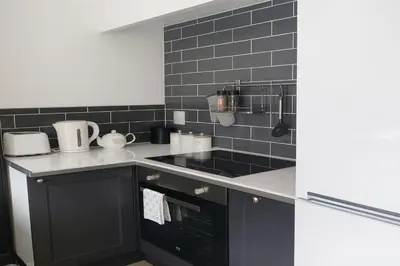 a kitchen with black cabinets and black tiles at 1 Bed Cottage-Sleeps 3-Pool-Pets-near St Ives in Camborne
