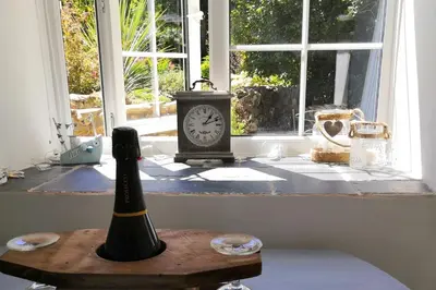 a clock sitting on a table in front of a window at 1 Bed Cottage-Sleeps 3-Pool-Pets-near St Ives in Camborne
