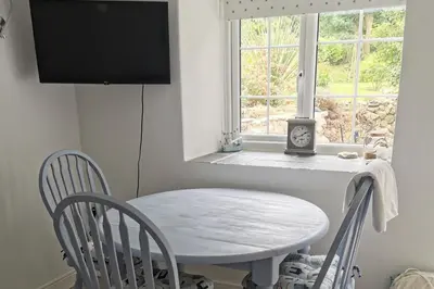 a white table and chairs in a room with a window at 1 Bed Cottage-Sleeps 3-Pool-Pets-near St Ives in Camborne