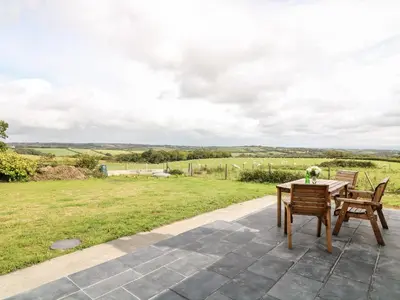 a patio with a table and chairs and a field at Summercourt in Launceston