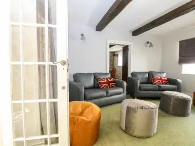 a living room with couches and ottomans at Culdrose Manor in Helston