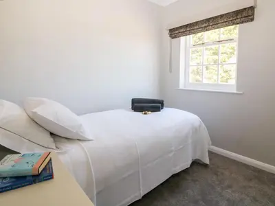 a white bed in a room with a window at Culdrose Manor in Helston