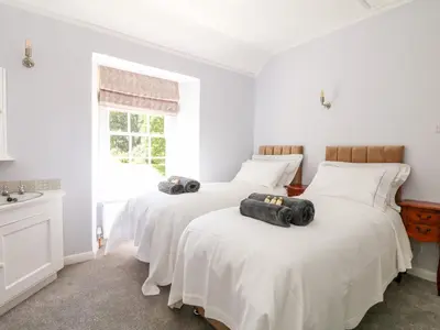 two beds in a bedroom with white walls at Culdrose Manor in Helston