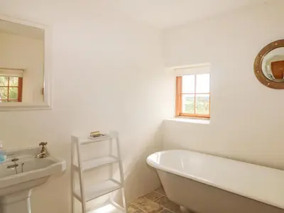 a white bathroom with a tub and a sink at Higher Roskorwell Cottage in Helston