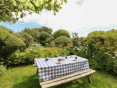 a picnic table with a blue and white checkered table cloth at Higher Roskorwell Cottage in Helston