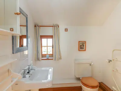 a white bathroom with a toilet and a sink at Higher Roskorwell Cottage in Helston