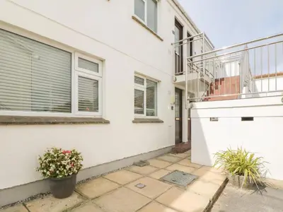 a white house with a balcony and a patio at 2 Europa Court in Newquay