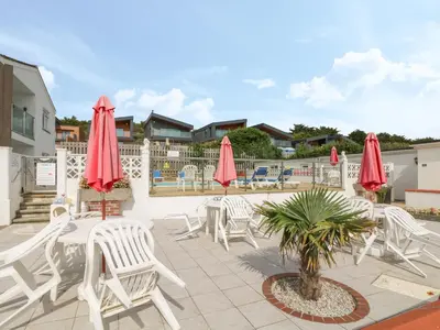 a patio with white chairs and red umbrellas at 2 Europa Court in Newquay