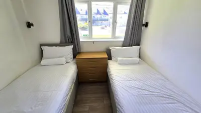 two twin beds in a room with a window at 10 Wheal Ramoth in Perranporth