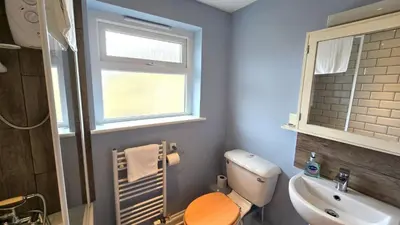 a bathroom with a toilet and a sink and a window at Gwel Angarder in Perranporth