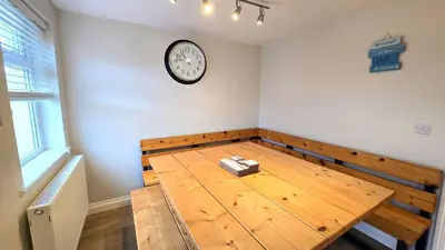a room with a wooden table with a clock on the wall at Gwel Angarder in Perranporth